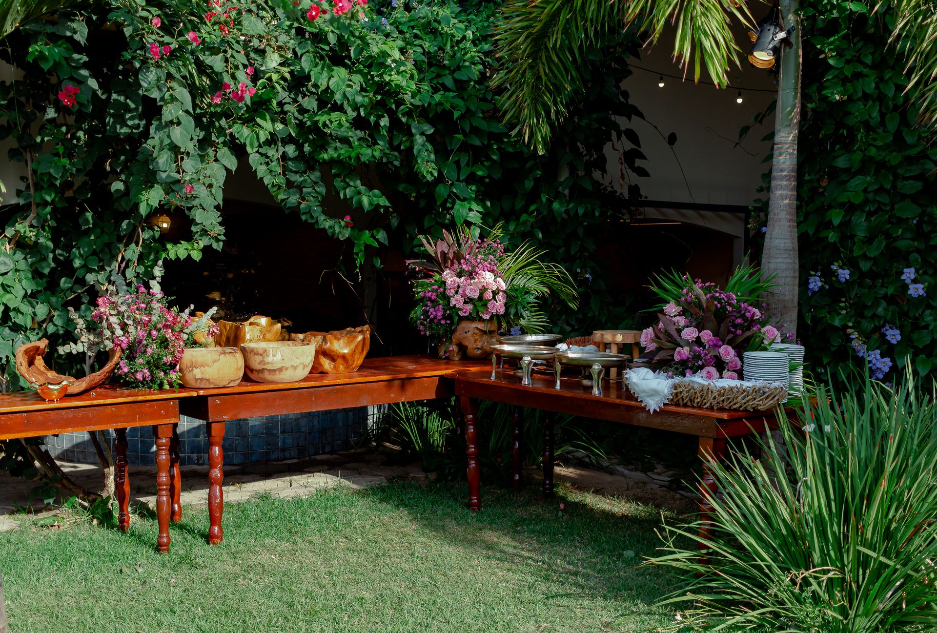 Buffet de catering ao ar livre com mesas em madeira e decoração floral